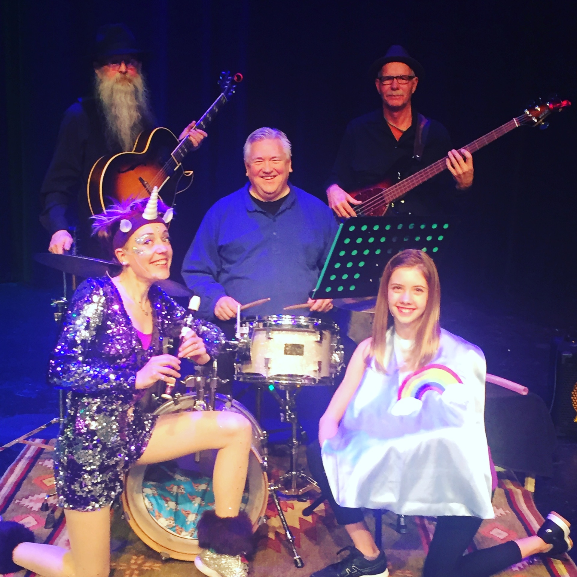 Jenifer in unicorn costume with the Rainbow Band and a young performer during The Magic Cape Show