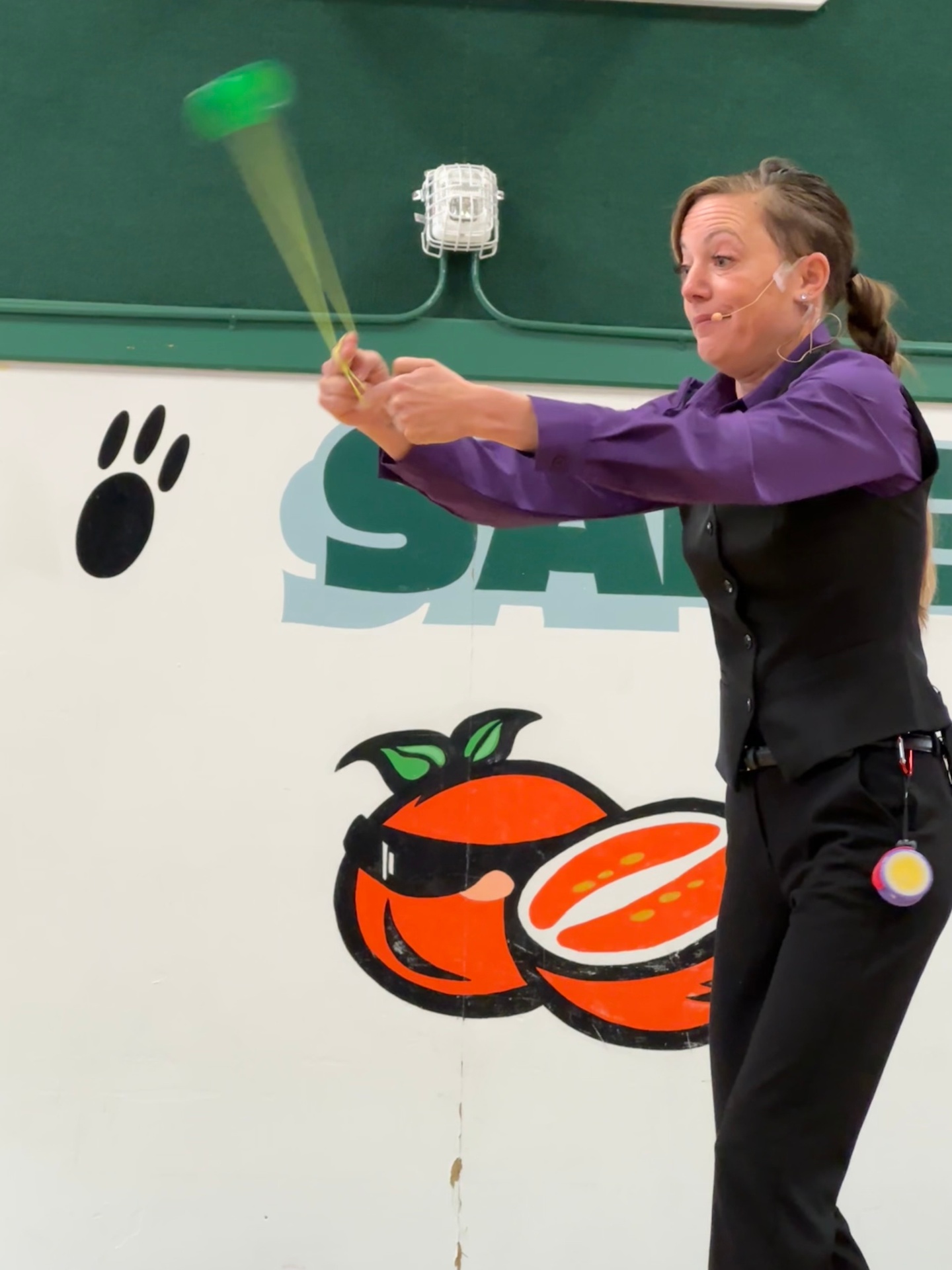 Jenifer performing a yo-yo trick in a purple shirt and black vest