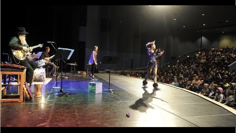 Jenifer performing The Magic Cape Show onstage for hundreds of elementary students