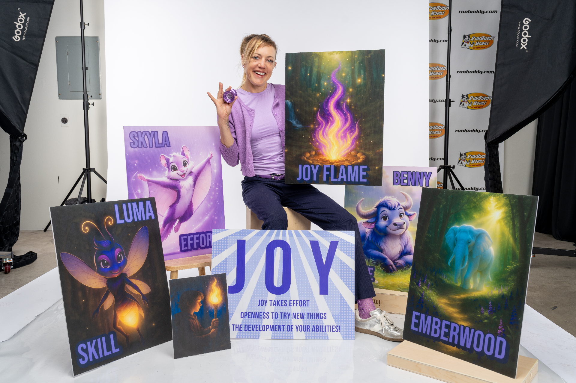 Jen Joy with SEL character posters — JOY Flame, Skyla, Luma, Benny, and Emberwood
