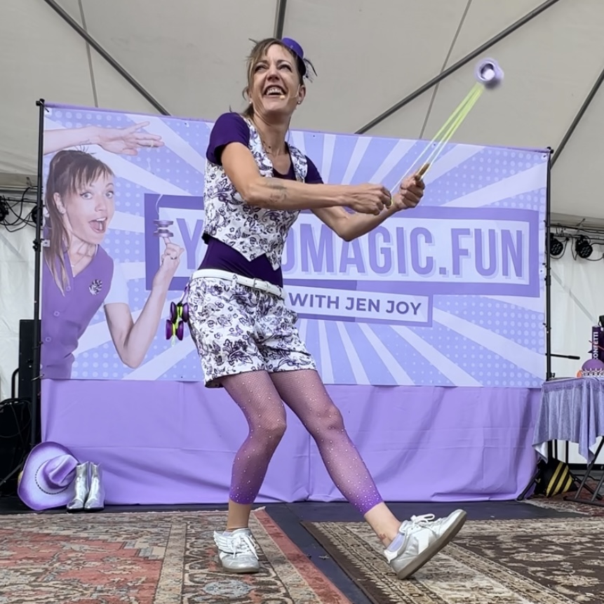 Jen Joy performing a yo-yo trick on a colorful festival stage